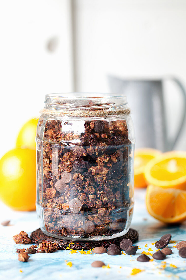 Choocolate orange granola in a jar with fresh oranges