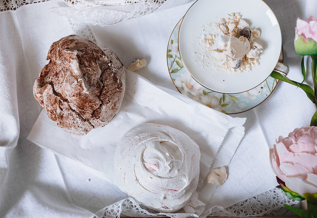 Pastel colored merengues, peonies, teacup on a wooden tray