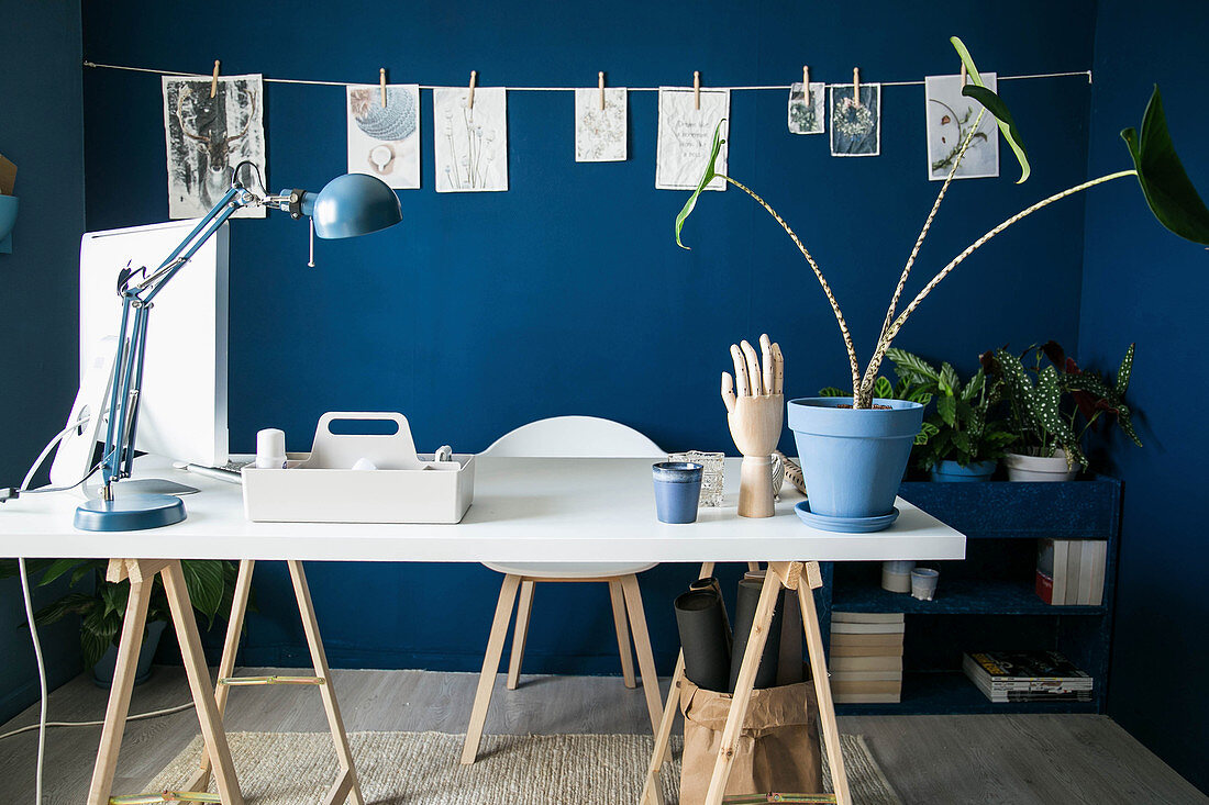 Weiße Tischplatte auf Holzböcken im Arbeitszimmer mit blauer Wand