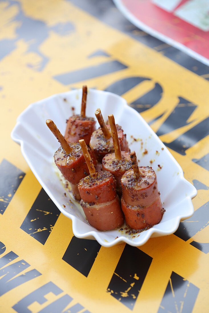 Grilled sausages with honey and mustard sauce on pretzel sticks