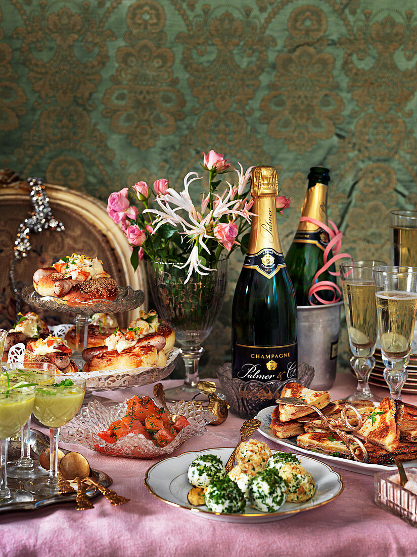 A New Year's Eve buffet with champagne, cheese balls, avocado soup, salmon, hot dogs, toast and flowers
