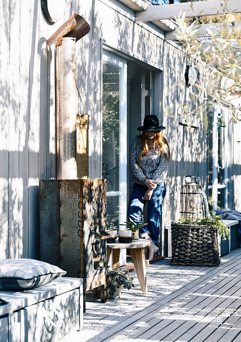 Wooden terrace with stove, woman stands at the door