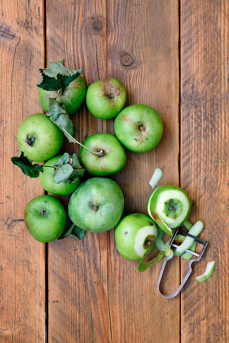 Green organic apples with leaves on a wooden background