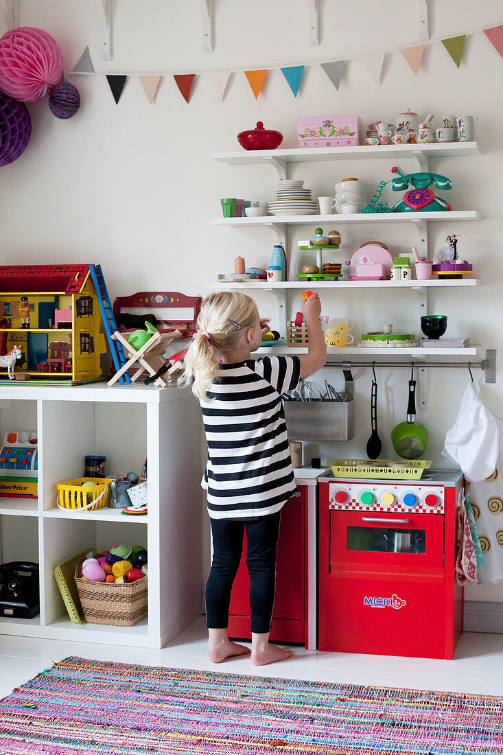 Blonde little girl in front of shelves in bedroom