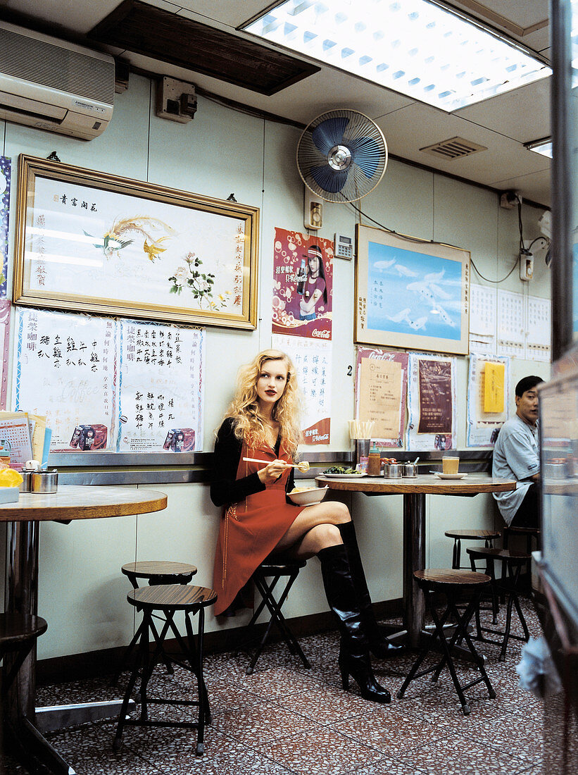 A blonde woman wearing an orange dress and a black jacket in a Chinese restaurant