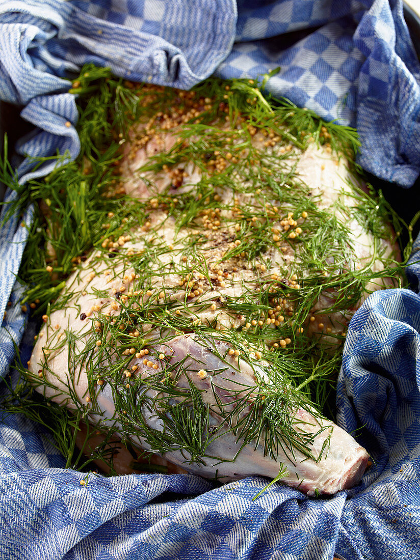 Raw shoulder of lamb being marinated in dill and spices