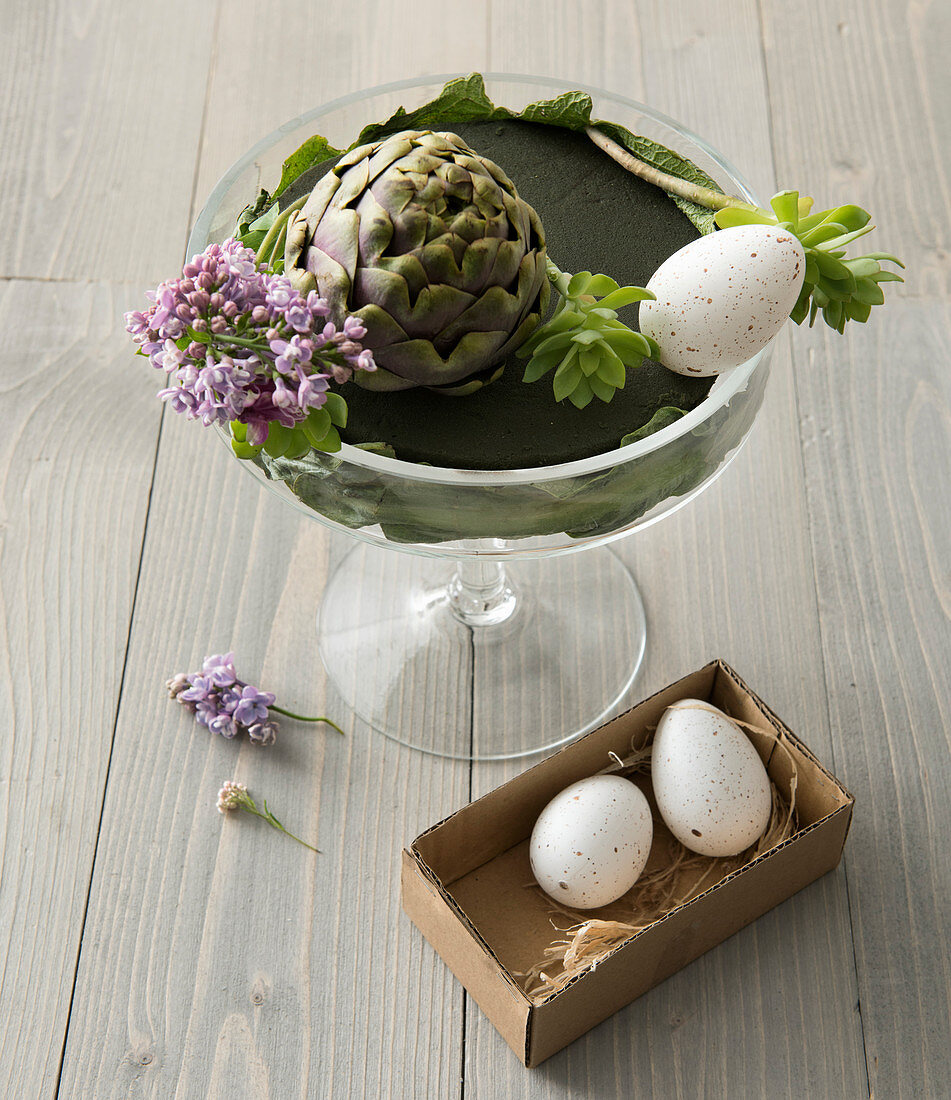 Unfertiges Blumenarrangement mit Artischocke und Eiern zu Ostern