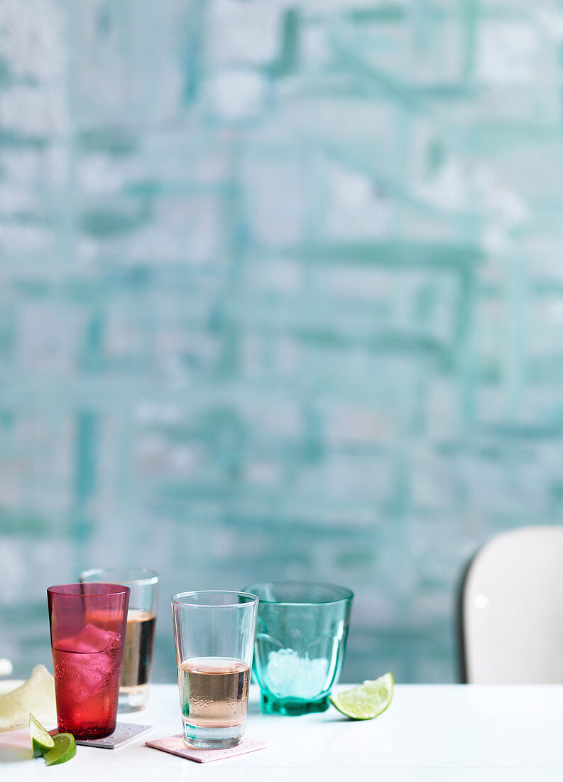 Farbige Gläser mit Getränken und Eiswürfeln, Limettenschnitze