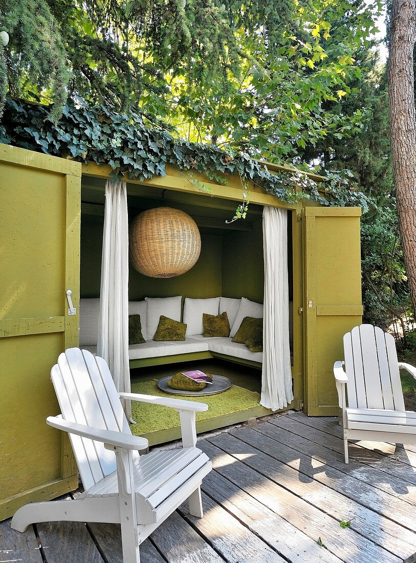 Two deckchairs on terrace outside climber-covered summerhouse