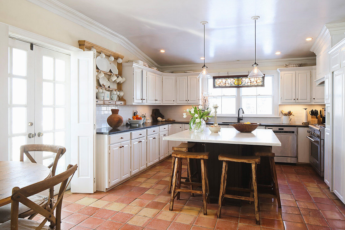 Wooden stool at island counter in American country-house kitchen