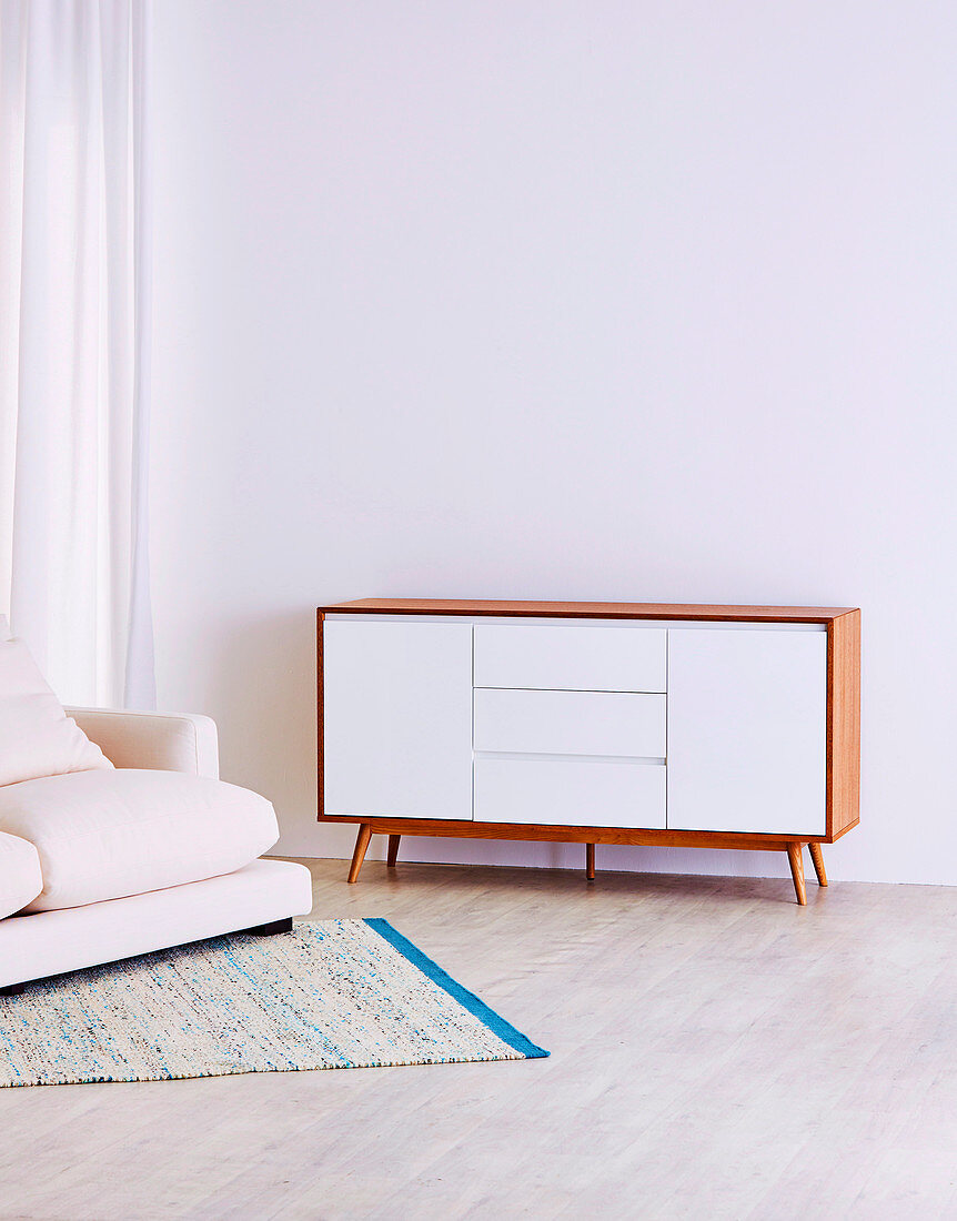 Retro Sideboard und Polstersofa vor weißer Wand