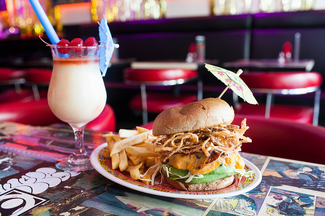 Vegan burger with avocado, soy cheese, fried onions, french fries and coconut and scotch cocktail