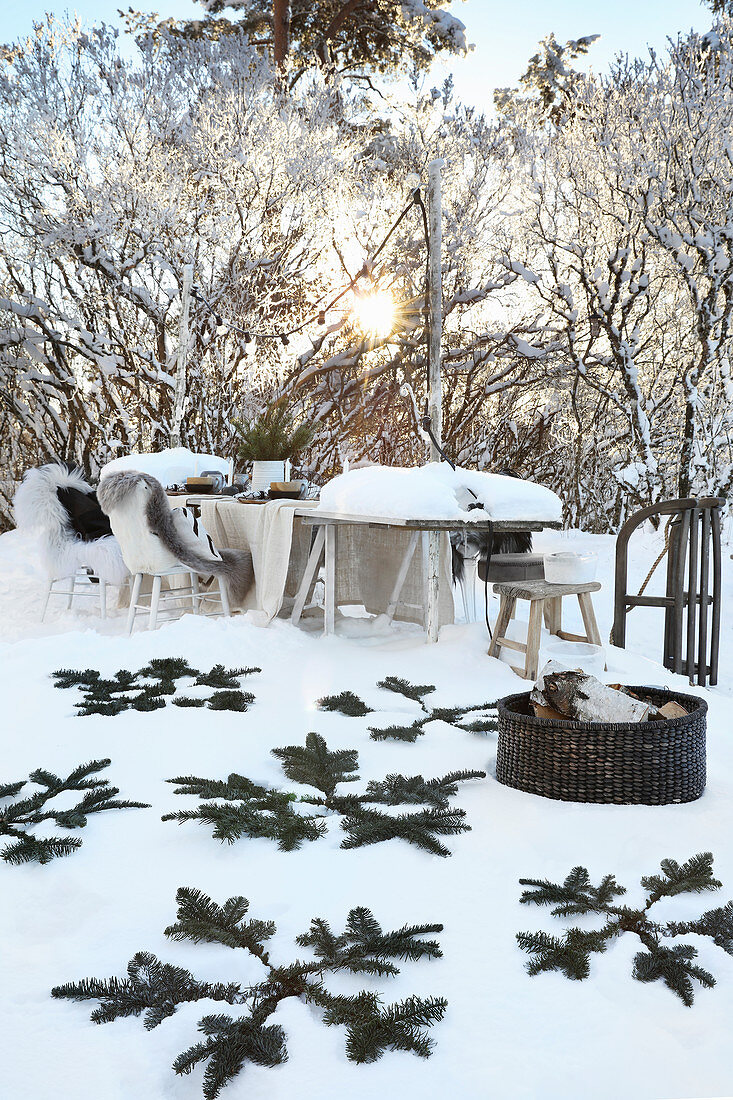 Kiefernzweige im Schnee, im Hintergrund Gedeckter Tisch