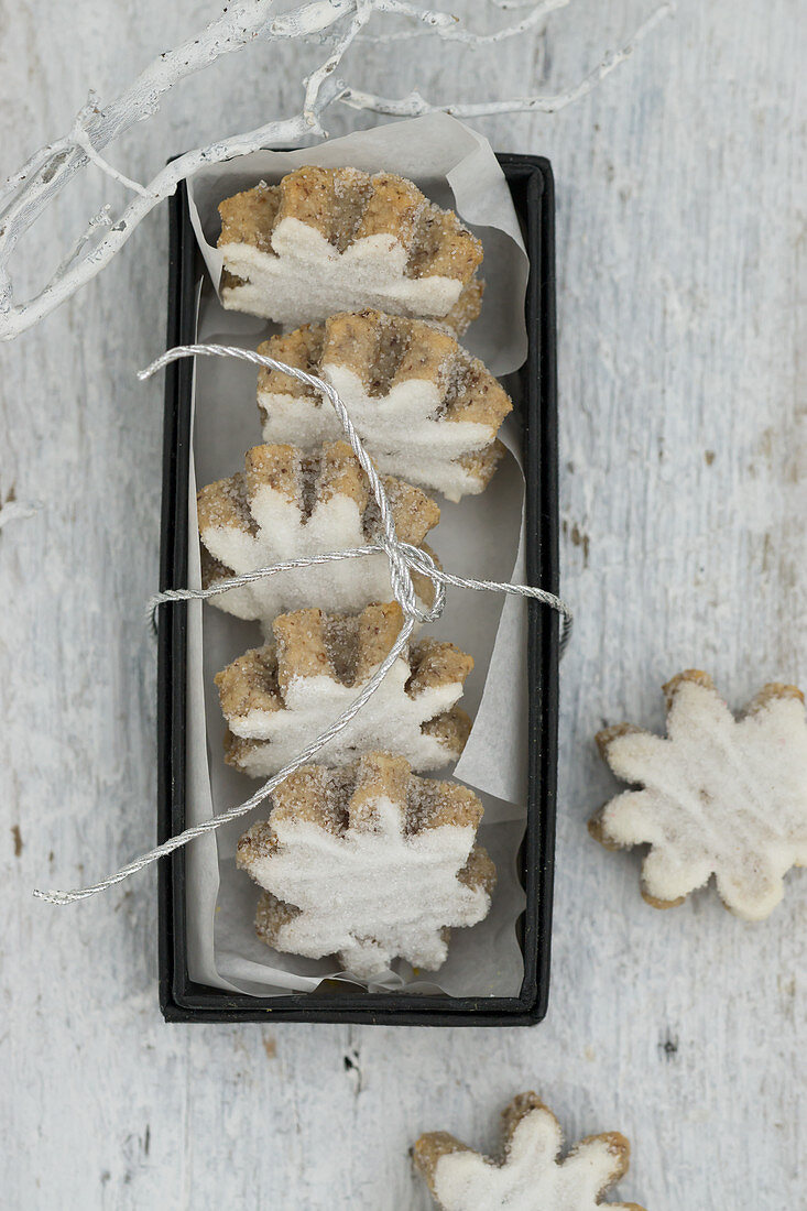 Blumenförmige Zimtplätzchen mit Zuckerglasur in einer Schachtel