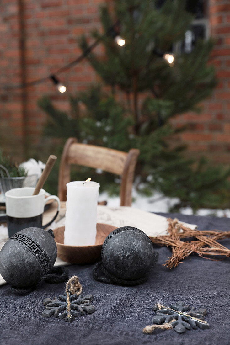 Tisch mit schwarzer Weihnachtsdeko und Kerze vor Backsteinhaus