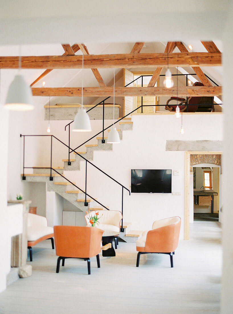 Eleganter Sitzbereich vor Betontreppe in Loft mit Holzbalken