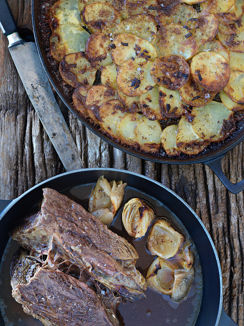 Beef steak in broth with onions and fried potatoes