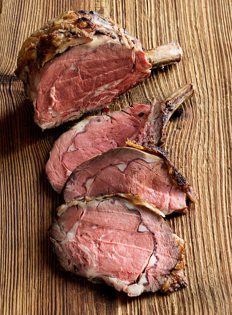 Prime rib steak, sliced, on a wooden surface