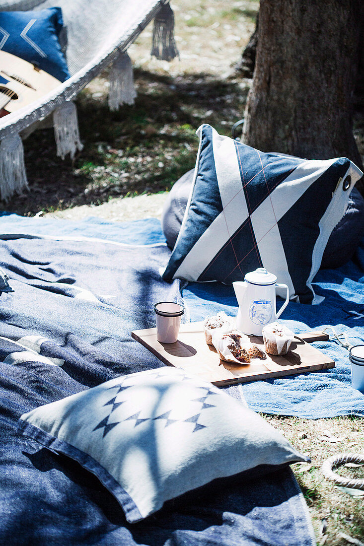 Picknickdecke mit Kissen unter einem Baum