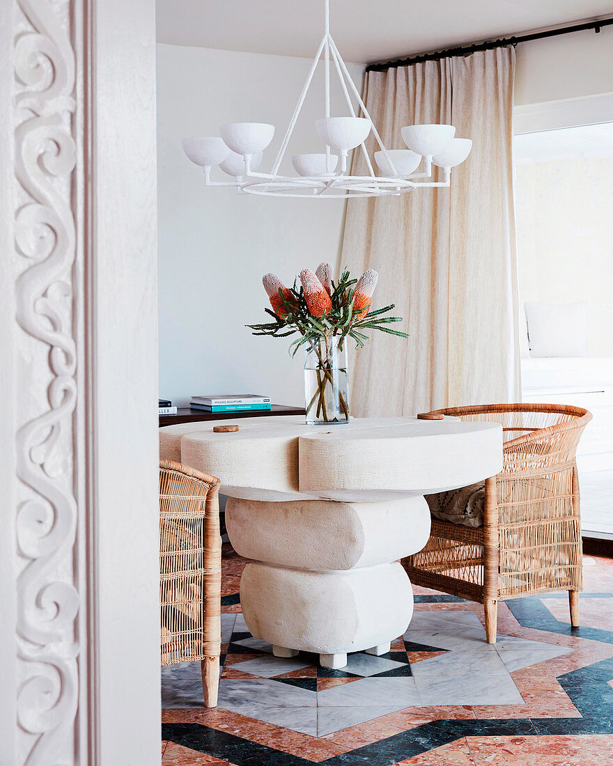 Designer table with rattan armchairs, bouquet of flowers and white chandelier