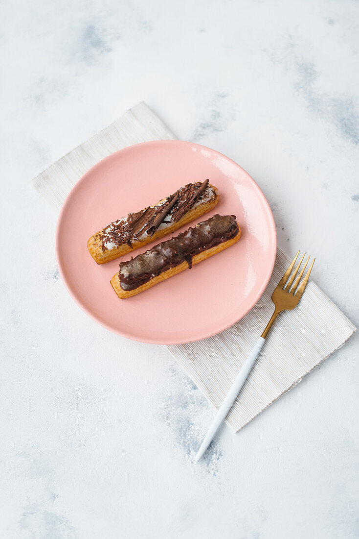 Two eclairs on a pink plate