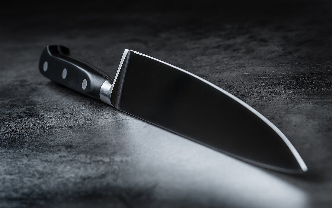 A meat knife with a sharp blade on a grey background