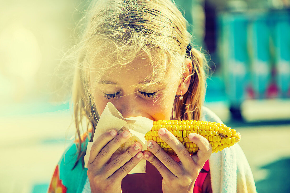 A girl eating a grilled corn cob