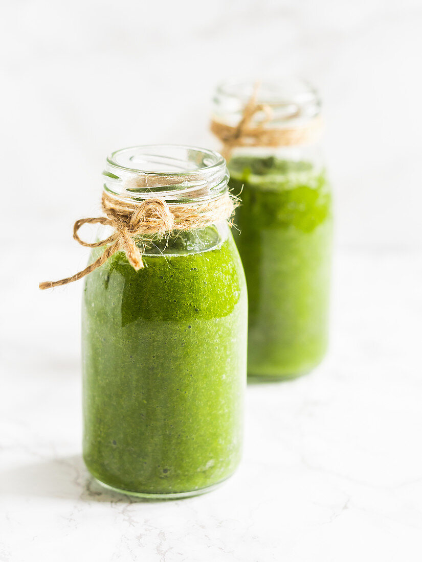 Two small bottles of healthy vegan green smoothie, made with baby spinach and kale