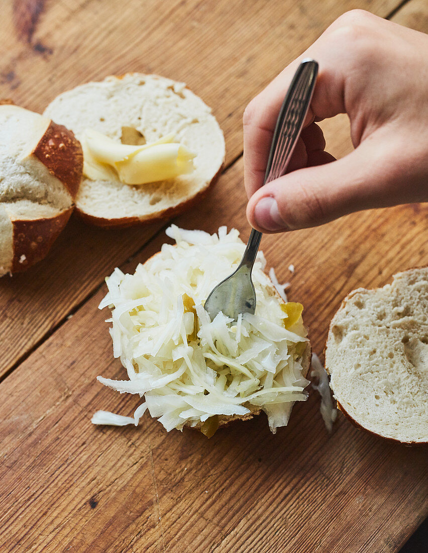 Coleslaw being placed on a lye bread roll