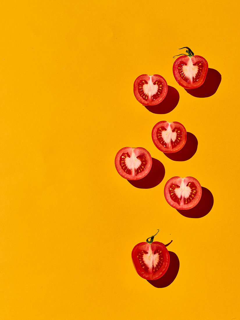 Halbierte Tomaten auf gelbem Hintergrund