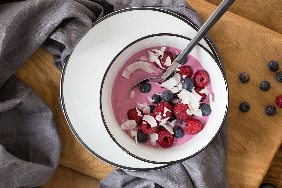 Joghurt mit Acaipulver, getoppt mit Himbeeren, Blaubeeren und Kokoschips