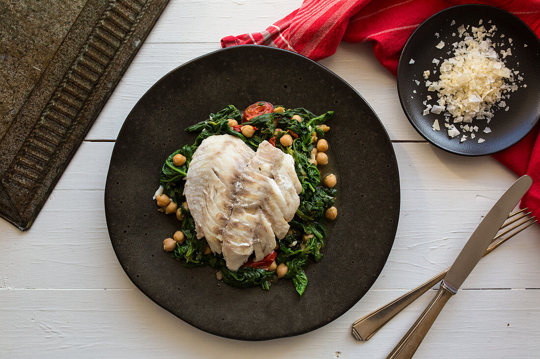 Rose fish on a bed of spinach with chickpeas, tomatoes and cumin