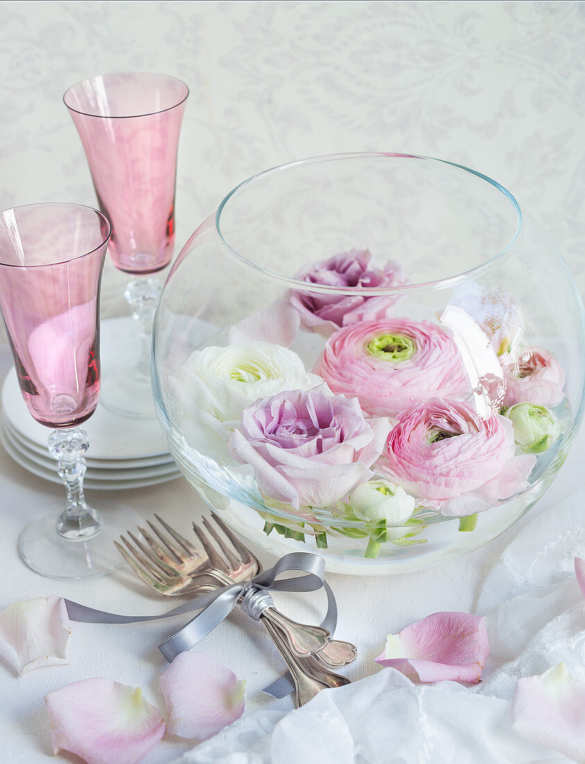 Wedding decorations: flowers in glass bowl, Champagne flutes and cutler on table