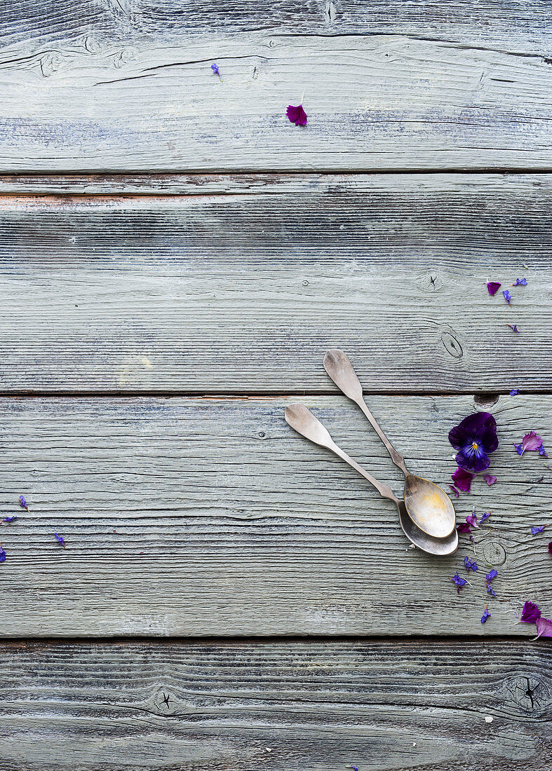 A wooden surface with a vintage teaspoons and flowers