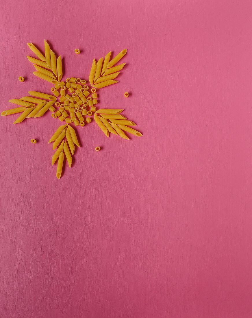 A star made of pasta shapes on a pink surface