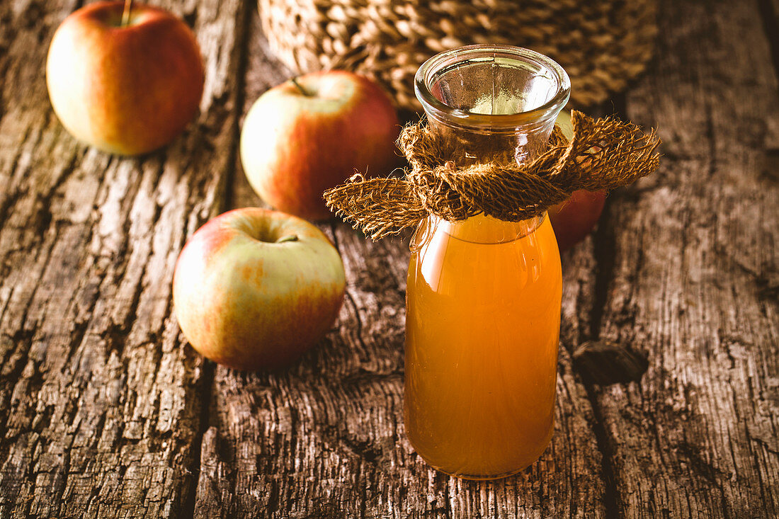 Apple vinegar in a glass carafe on a wooden surface