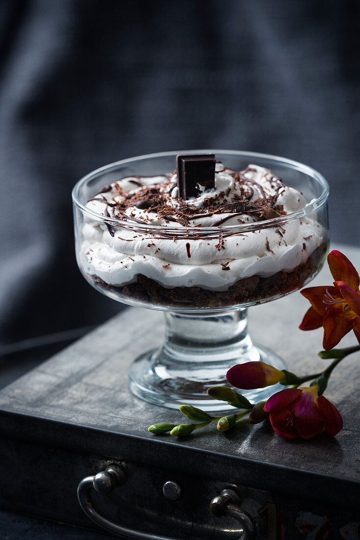 Coffee and chocolate cake, banana cream and chocolate decorations in a glass bowl (vegan)