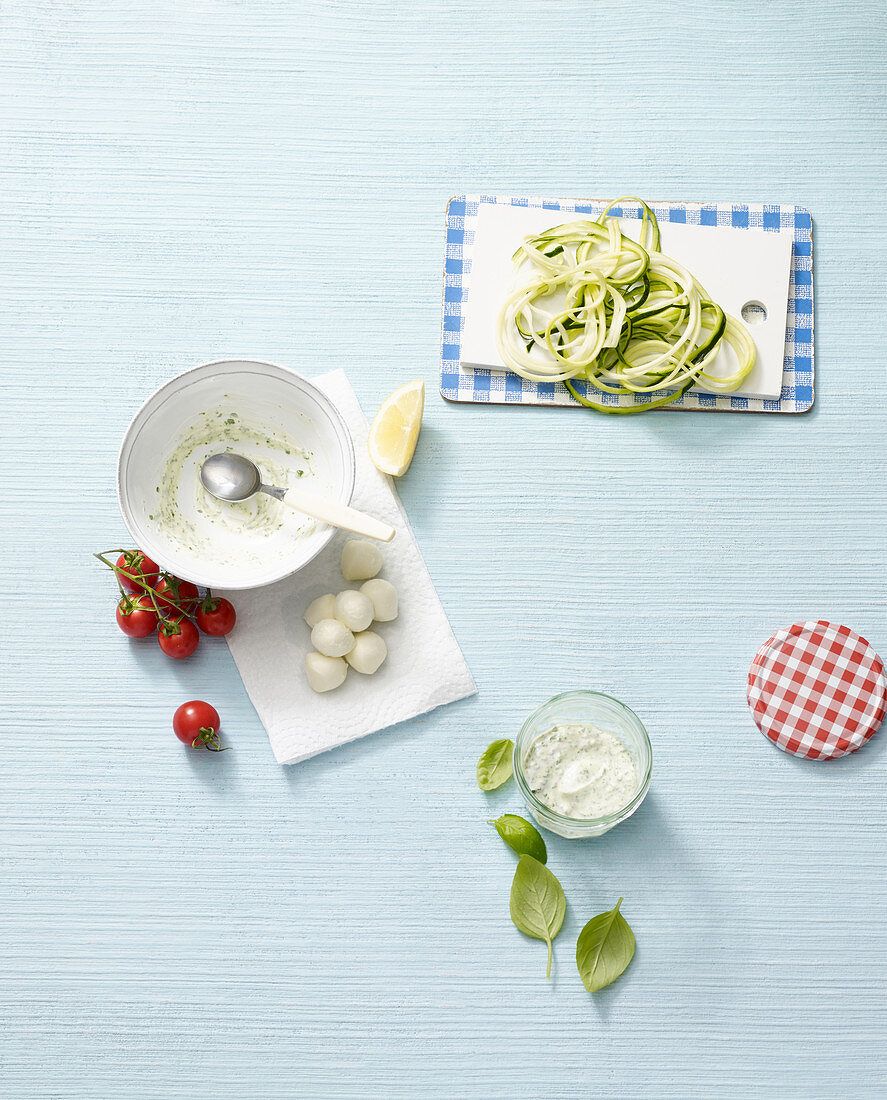 ingredients for courgette salad with tomatoes, mozzarella and pesto