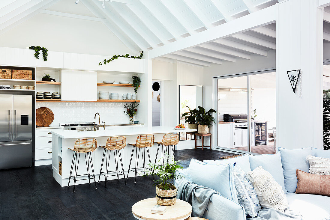 Cushions on sofa and white kitchen with island counter in open-plan interior