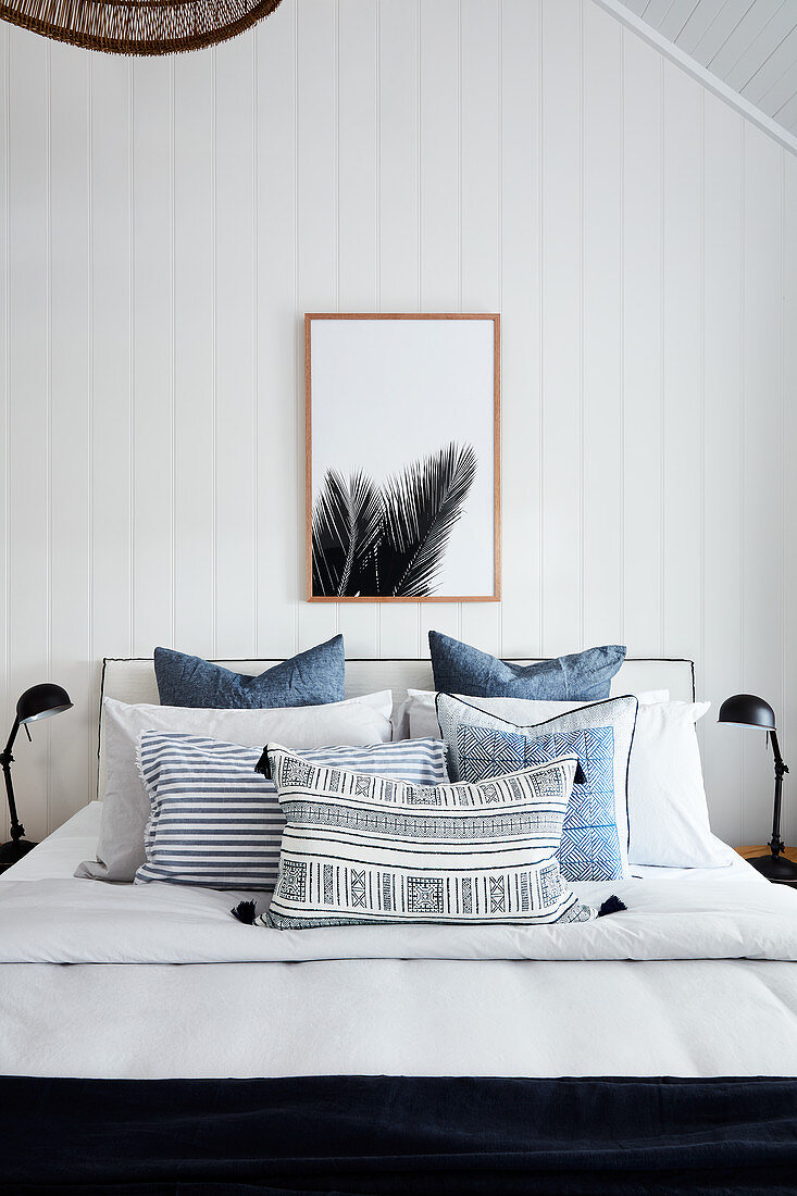 Blue bedspread on double bed with white wood-clad walls