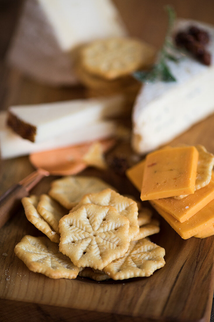 Crackers and various types of cheese on a wooden board