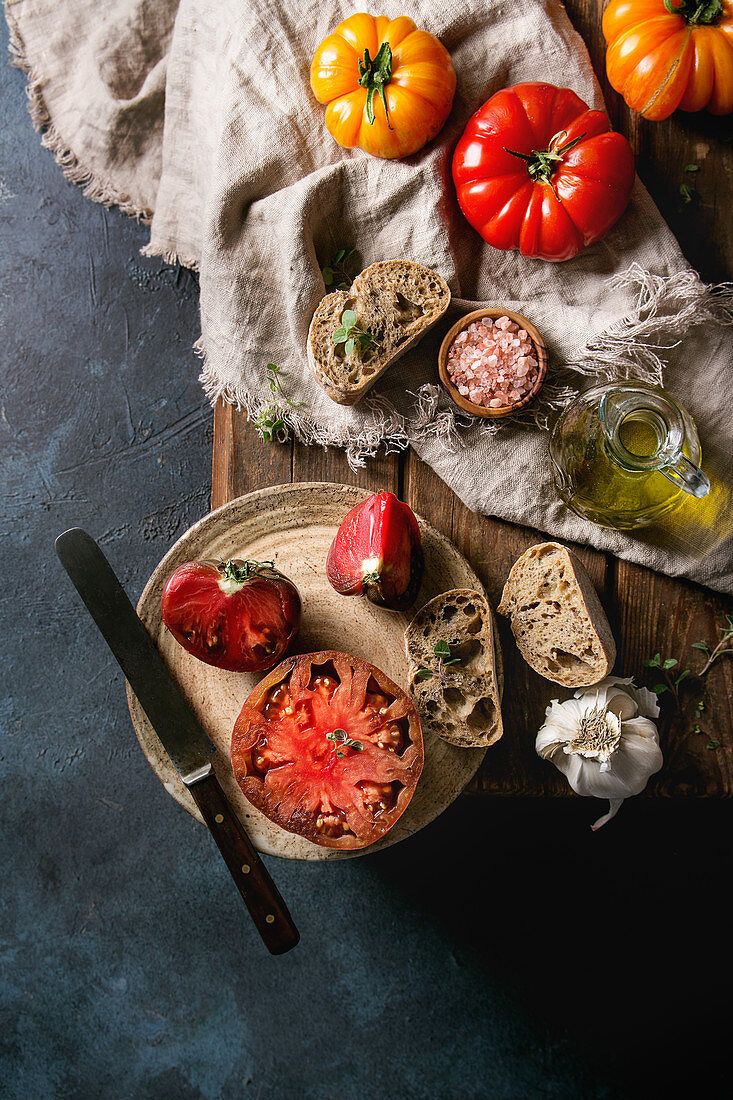 Red and yellow organic tomatoes with olive oil, garlic, salt and bread for salad or bruschetta