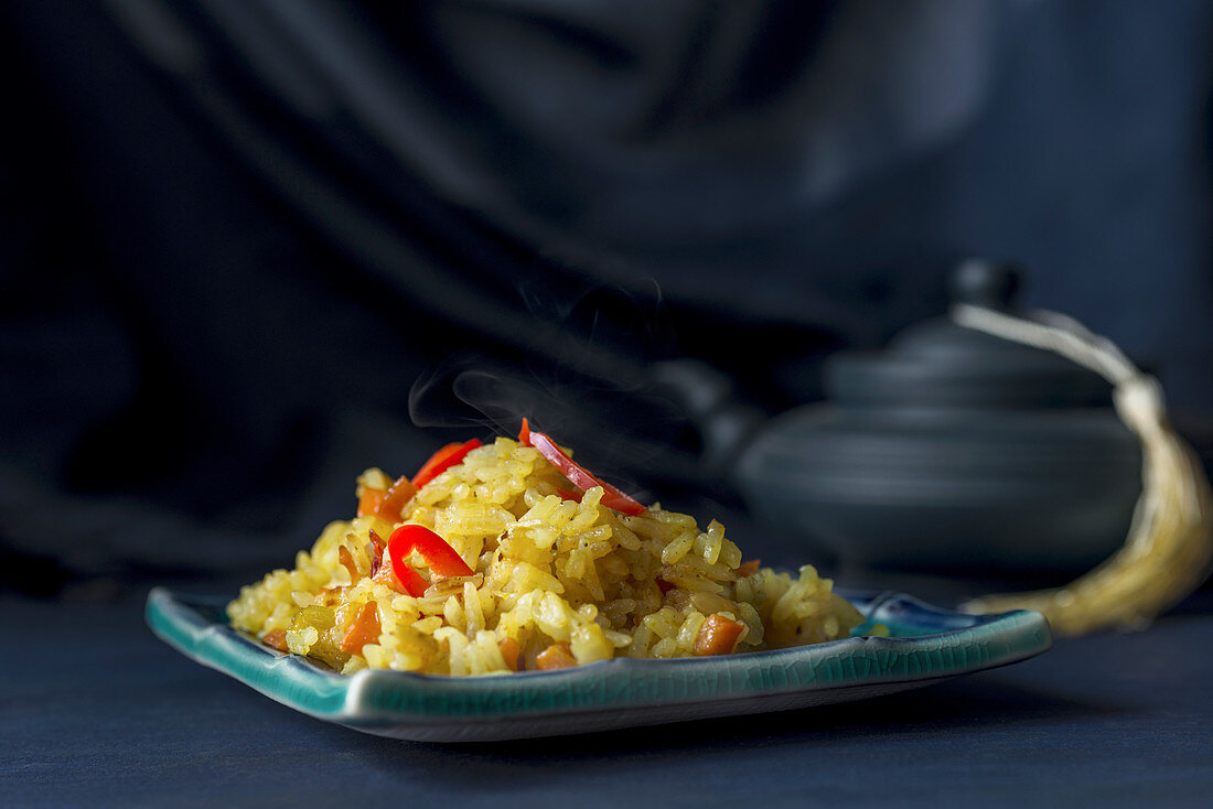 No-meat pilaf garnished with red chili peppers on a dark blue background