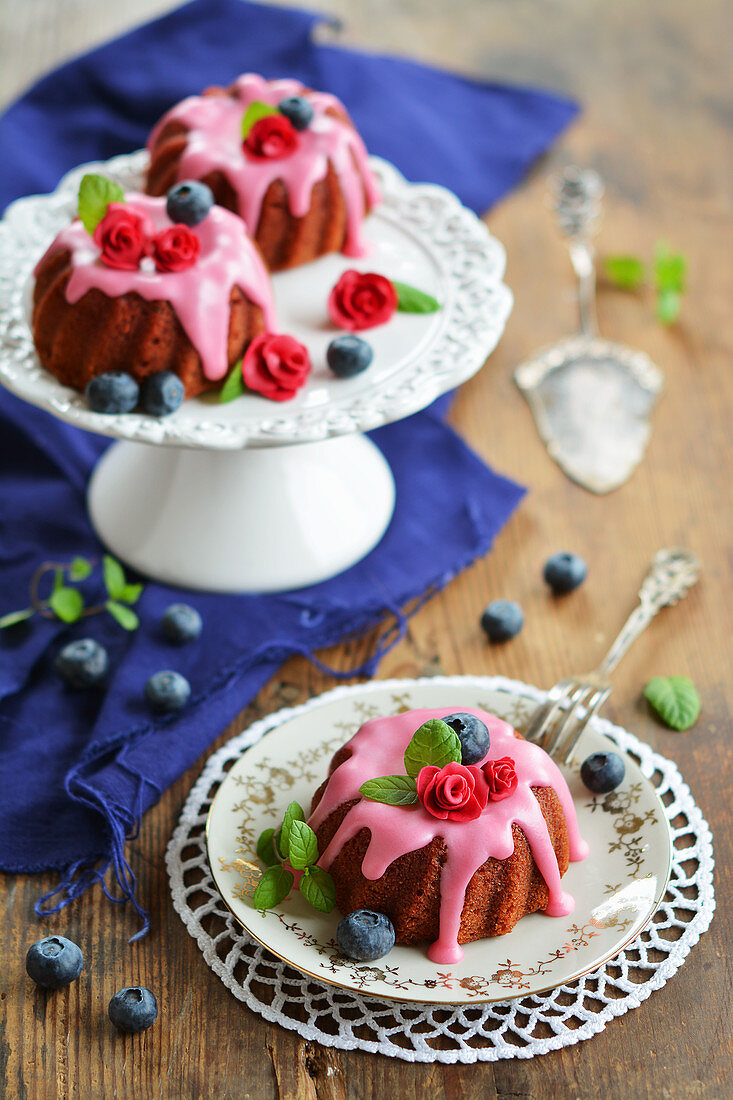 Three mini gugelhupfs with beetroot, frosting, sugar flowers, fresh blueberries and mint