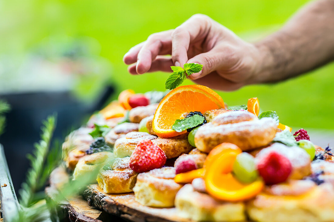 Buffet mit Kleingebäck, dekoriert mit frischen Früchten, Beeren und Kräutern