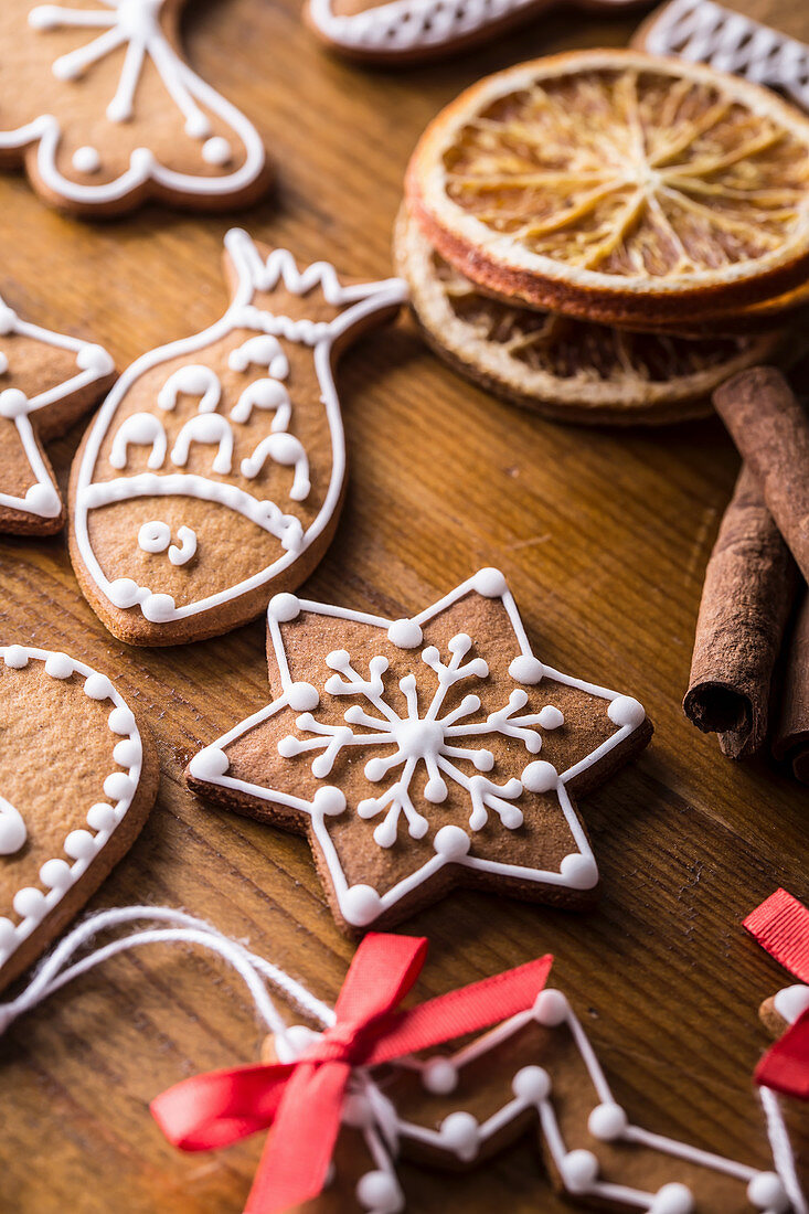 Verzierte Lebkuchen, getrocknete Orangenscheiben und Zimtstangen auf Holztisch