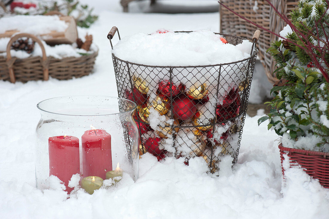 Basket with Christmas baubles and lantern in the snow