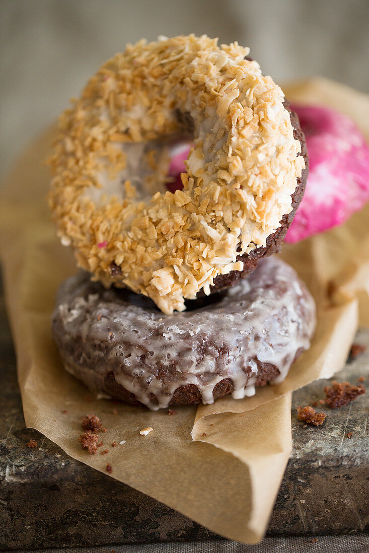 Coconut, chocolate and pomegranate donuts on paper