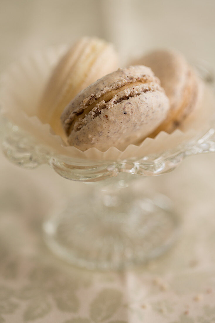 Various macarons in paper cups and a glass bowl