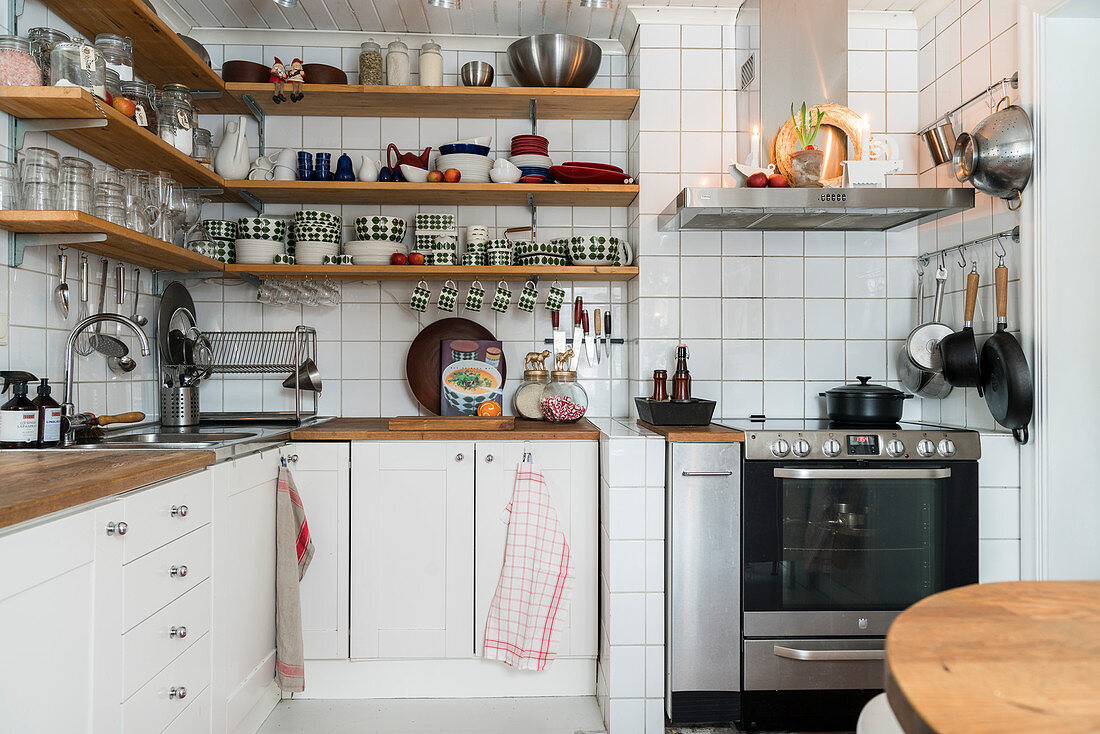 Shelves on walls above base units and white wall tiles in kitchen